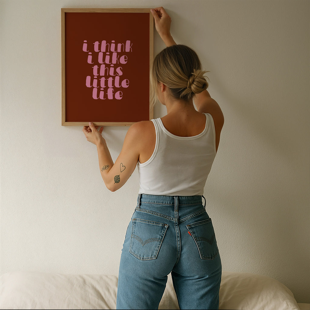 I Think I Like This Little Life Poster – Hol dir den Vibe von Selbstliebe, Ruhe und kleinen Glücksmomenten im Alltag. Die weiche, verspielte Typografie in zartem Rosa auf warmem Braunton wirkt modern, emotional und bringt eine cozy, positive Stimmung in dein Zuhause. Ob im Wohnzimmer, Schlafzimmer, Büro oder Flur – der Print sorgt sofort für eine warme, stilvolle Atmosphäre und wird zu einem dezenten Hingucker an jeder Wand.