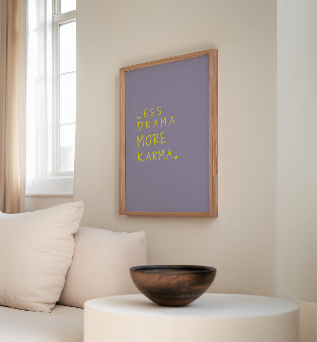 Modernes Quote Poster Less Drama More Karma im Holzrahmen an heller Wohnzimmerwand